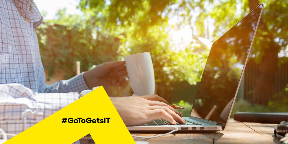 Person working from home, outside with laptop and coffee using remote IT support tools