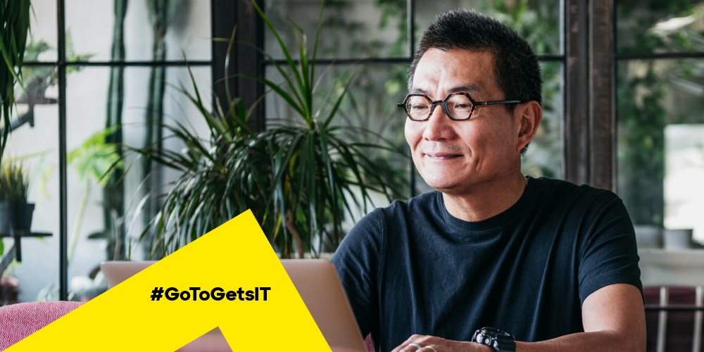 Un homme qui travaille sur un ordinateur portable dans une pièce remplie de plantes et qui apprend comment réparer les erreurs DNS