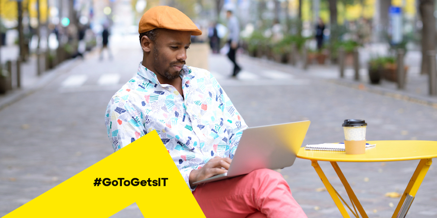 Man working on a laptop in an outdoor café using IT automation to make IT easier