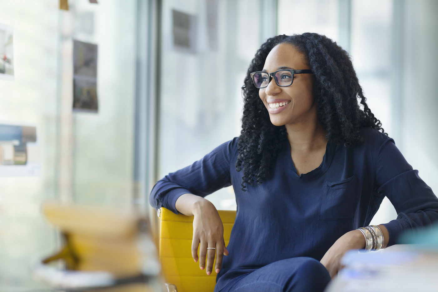 Woman at desk smiling over her shoulder at #GoToGetsIT research about improving the relationship between employees and IT departments