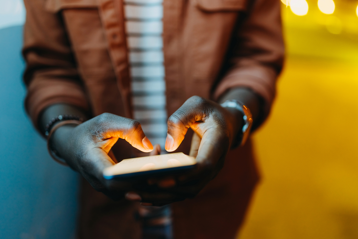 Man holding smartphone in dimly lit area using remote access protected by zero trust security