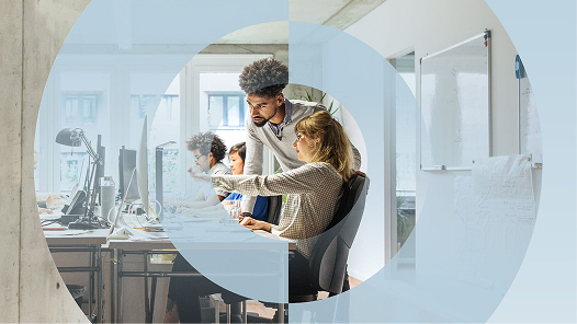 Dos compañeros de trabajo en una oficina consultando el informe El pulso del trabajo en 2025 en un ordenador de sobremesa.